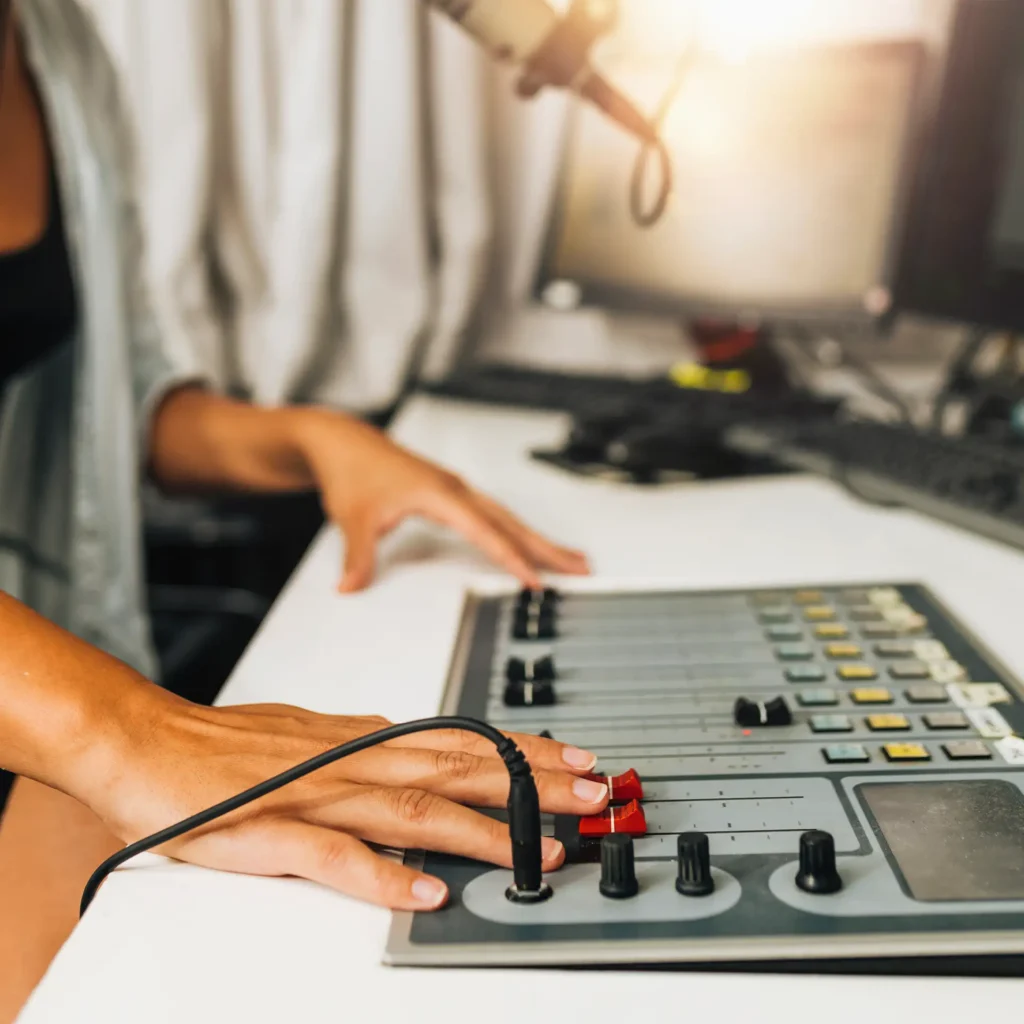 Hände bedienen ein Mischpult in einem Streaming-Setup